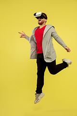 Image showing Full length portrait of young successfull high jumping man gesturing isolated on yellow studio background