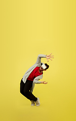 Image showing Full length portrait of young successfull high jumping man gesturing isolated on yellow studio background