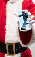 Image showing Close up hands of Santa Claus holding device with riding deliveryman on the screen