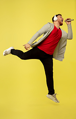 Image showing Full length portrait of young successfull high jumping man gesturing isolated on yellow studio background