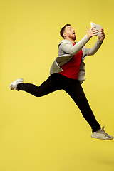 Image showing Full length portrait of young successfull high jumping man gesturing isolated on yellow studio background