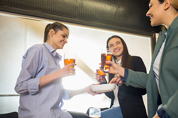 Image showing Happy co-workers celebrating corporate event after tensioned work day. Look delighted, friendly, cheerful