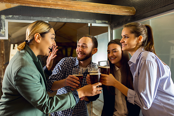 Image showing Happy co-workers celebrating corporate event after tensioned work day. Look delighted, friendly, cheerful