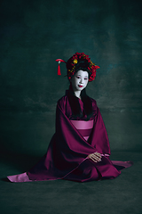 Image showing Young japanese woman as geisha on dark green background. Retro style, comparison of eras concept.