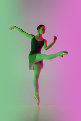 Image showing Young and graceful ballet dancer isolated on gradient pink-green studio background in neon light. Art in motion