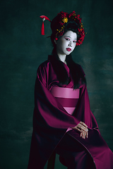 Image showing Young japanese woman as geisha on dark green background. Retro style, comparison of eras concept.