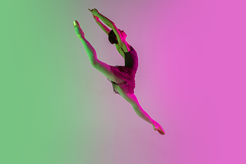 Image showing Young and graceful ballet dancer isolated on gradient pink-green studio background in neon light. Art in motion