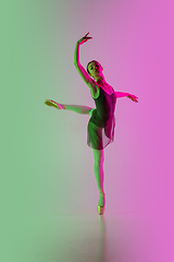 Image showing Young and graceful ballet dancer isolated on gradient pink-green studio background in neon light. Art in motion