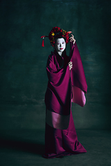 Image showing Young japanese woman as geisha on dark green background. Retro style, comparison of eras concept.