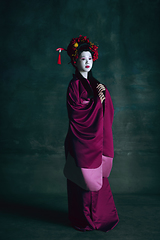 Image showing Young japanese woman as geisha on dark green background. Retro style, comparison of eras concept.