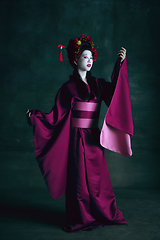 Image showing Young japanese woman as geisha on dark green background. Retro style, comparison of eras concept.