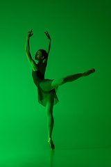 Image showing Young and graceful ballet dancer isolated on gradient green studio background in neon light. Art in motion
