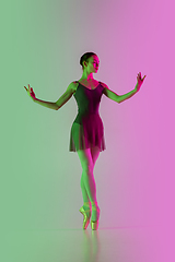 Image showing Young and graceful ballet dancer isolated on gradient pink-green studio background in neon light. Art in motion