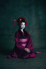 Image showing Young japanese woman as geisha on dark green background. Retro style, comparison of eras concept.