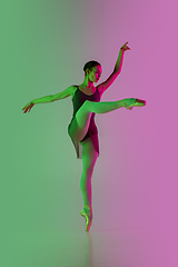 Image showing Young and graceful ballet dancer isolated on gradient pink-green studio background in neon light. Art in motion