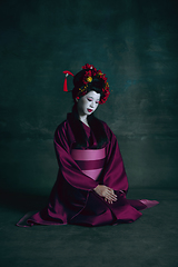 Image showing Young japanese woman as geisha on dark green background. Retro style, comparison of eras concept.