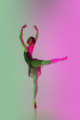 Image showing Young and graceful ballet dancer isolated on gradient pink-green studio background in neon light. Art in motion