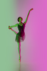 Image showing Young and graceful ballet dancer isolated on gradient pink-green studio background in neon light. Art in motion