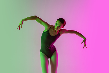 Image showing Young and graceful ballet dancer isolated on gradient pink-green studio background in neon light. Art in motion