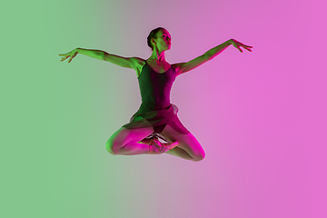 Image showing Young and graceful ballet dancer isolated on gradient pink-green studio background in neon light. Art in motion