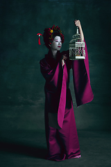 Image showing Young japanese woman as geisha on dark green background. Retro style, comparison of eras concept.