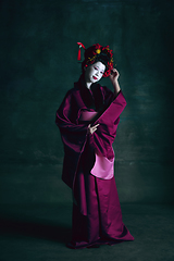 Image showing Young japanese woman as geisha on dark green background. Retro style, comparison of eras concept.