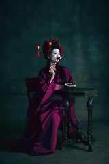 Image showing Young japanese woman as geisha on dark green background. Retro style, comparison of eras concept.