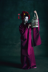 Image showing Young japanese woman as geisha on dark green background. Retro style, comparison of eras concept.