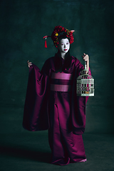 Image showing Young japanese woman as geisha on dark green background. Retro style, comparison of eras concept.