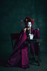 Image showing Young japanese woman as geisha on dark green background. Retro style, comparison of eras concept.