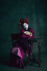 Image showing Young japanese woman as geisha on dark green background. Retro style, comparison of eras concept.