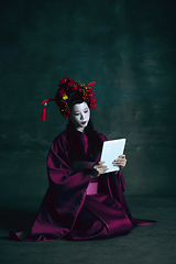 Image showing Young japanese woman as geisha on dark green background. Retro style, comparison of eras concept.