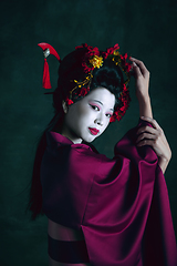 Image showing Young japanese woman as geisha on dark green background. Retro style, comparison of eras concept.