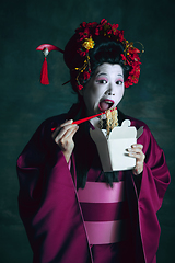 Image showing Young japanese woman as geisha on dark green background. Retro style, comparison of eras concept.