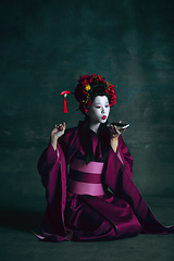 Image showing Young japanese woman as geisha on dark green background. Retro style, comparison of eras concept.