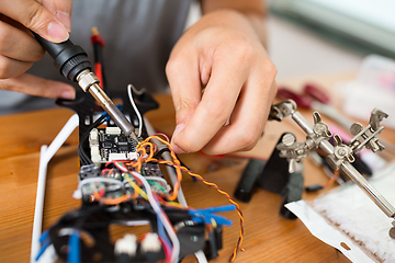 Image showing Man using welding for connecting wire on board of the drone