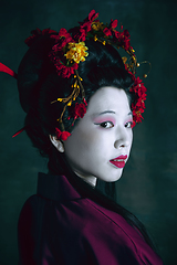 Image showing Young japanese woman as geisha on dark green background. Retro style, comparison of eras concept.