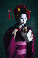 Image showing Young japanese woman as geisha on dark green background. Retro style, comparison of eras concept.