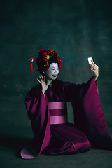 Image showing Young japanese woman as geisha on dark green background. Retro style, comparison of eras concept.