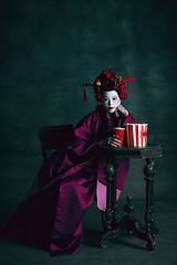 Image showing Young japanese woman as geisha on dark green background. Retro style, comparison of eras concept.