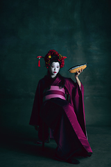 Image showing Young japanese woman as geisha on dark green background. Retro style, comparison of eras concept.