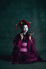 Image showing Young japanese woman as geisha on dark green background. Retro style, comparison of eras concept.