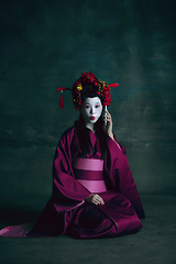 Image showing Young japanese woman as geisha on dark green background. Retro style, comparison of eras concept.