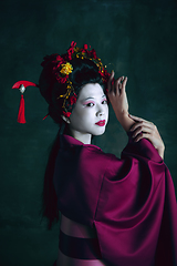 Image showing Young japanese woman as geisha on dark green background. Retro style, comparison of eras concept.