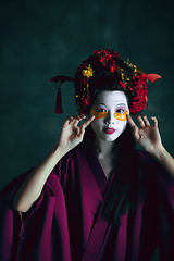 Image showing Young japanese woman as geisha on dark green background. Retro style, comparison of eras concept.