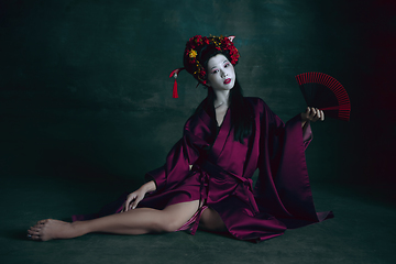 Image showing Young japanese woman as geisha on dark green background. Retro style, comparison of eras concept.