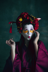 Image showing Young japanese woman as geisha on dark green background. Retro style, comparison of eras concept.