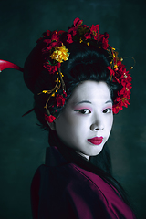 Image showing Young japanese woman as geisha on dark green background. Retro style, comparison of eras concept.