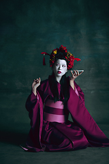 Image showing Young japanese woman as geisha on dark green background. Retro style, comparison of eras concept.