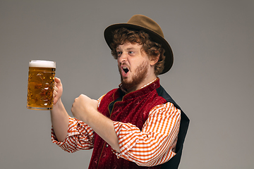 Image showing Happy smiling man dressed in traditional Austrian or Bavarian costume gesturing isolated on grey studio background